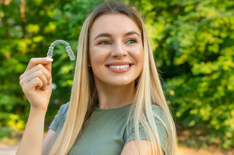 invisalign, women holding a clear aligner, cosmetic dentistry