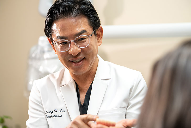 doctor holding a model of full arch implants to show patient